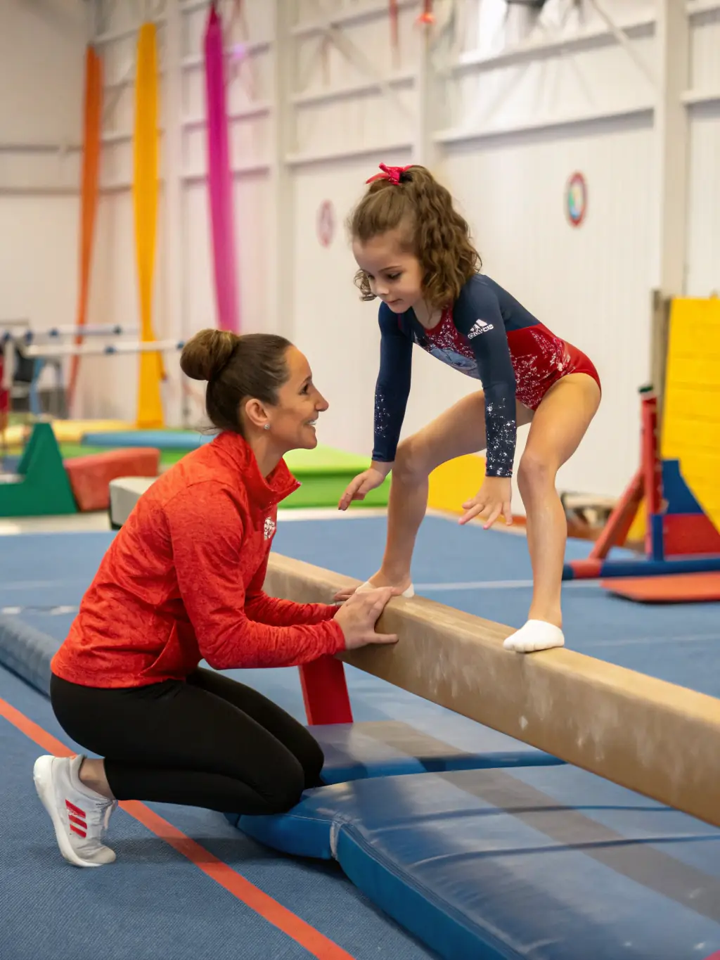 A photo of a gymnastics coach demonstrating proper technique to a group of young athletes, emphasizing safety and skill development.